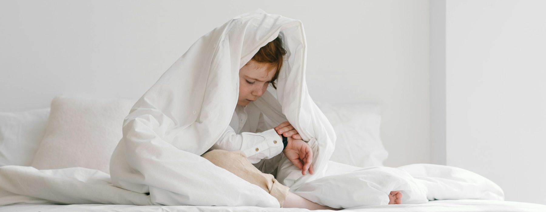 Little boy sleeping in bed with a teddy bear on blue bedding