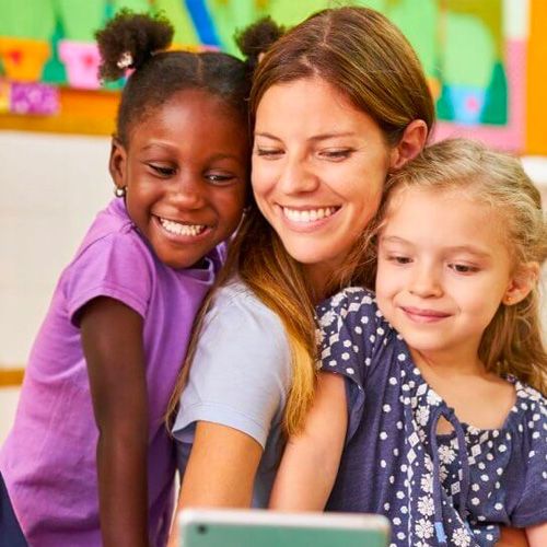 A woman and two girls smiling, looking at a tablet