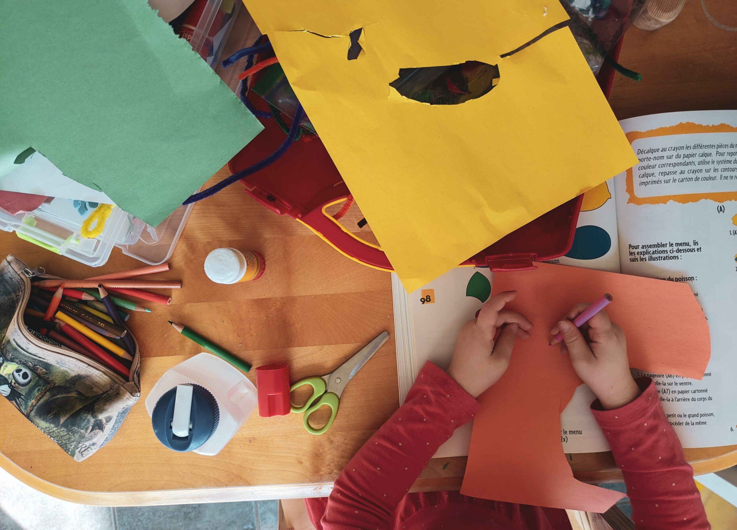 A child is playing with craft paper on a table