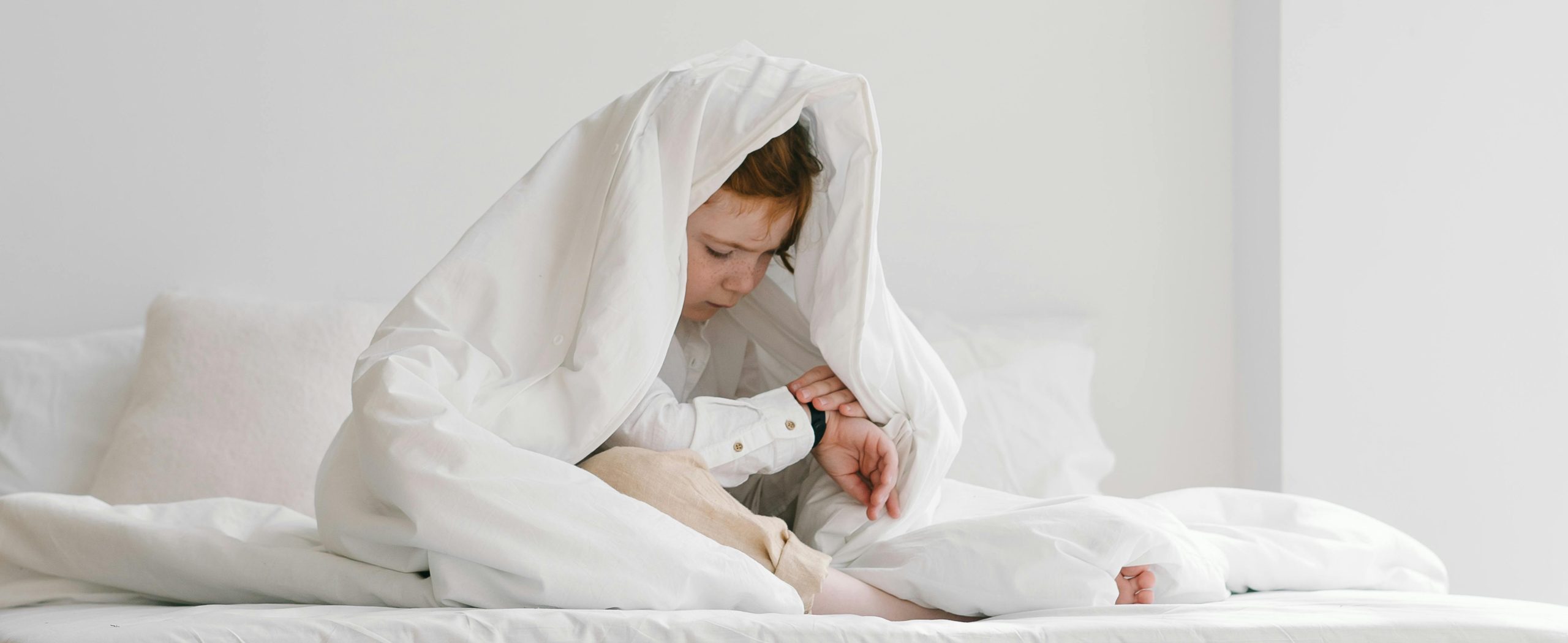 Little boy sleeping in bed with a teddy bear on blue bedding