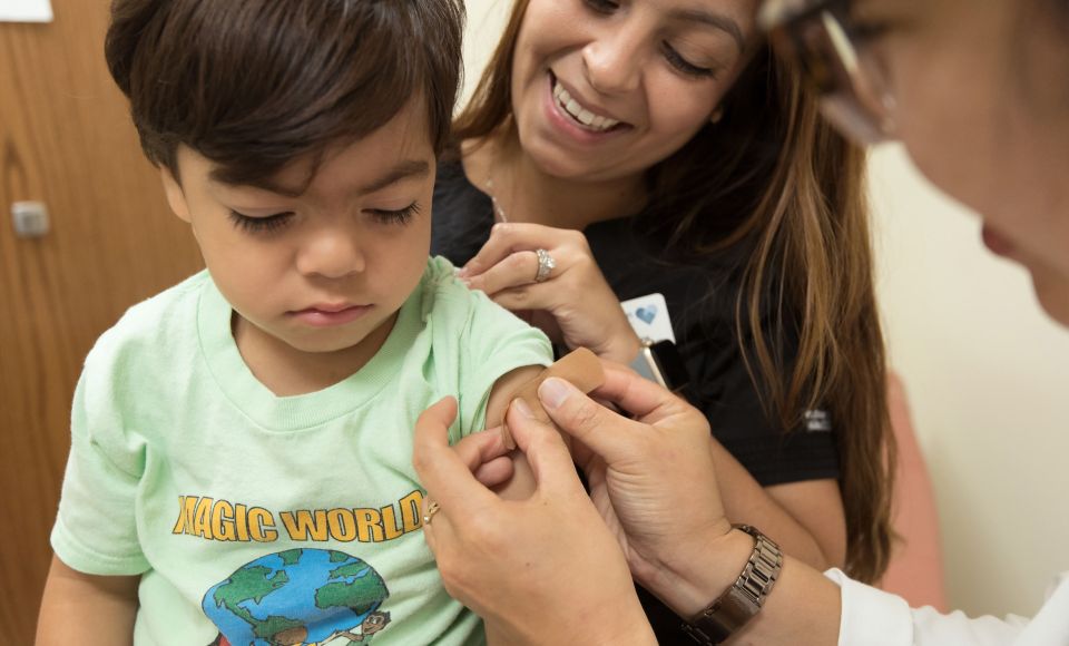 A little boy getting his temperature checked by a woman